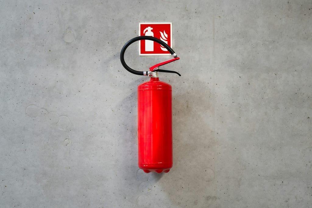 Extincteur fixé à un mur de béton sous son panneau de signalisation.